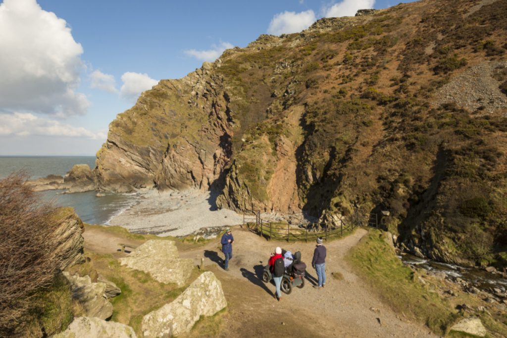 Visitors at the mouth of the River Heddon at Heddon Valley, Devon. Towering cliffs, coves and a wooded valley within Exmoor National Park